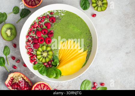Frische grüne Smoothie-Schüssel mit Spinat, Mango, Kiwi und Himbeere. Gesunde vegane Rohkost Stockfoto