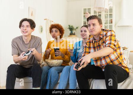 Heimparty. Fröhliche Gruppe von Freunden, die zu Hause Videospiele spielen. Fröhliche Gruppen-Freunde, die gemeinsam viel Spaß haben. Frien Stockfoto
