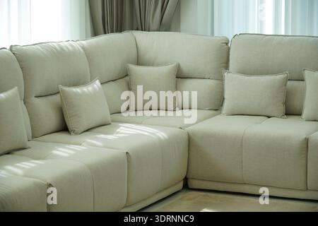 Weiße Couch mit Kissen drauf. Die Couch ist in einem Wohnzimmer mit Fenster Stockfoto