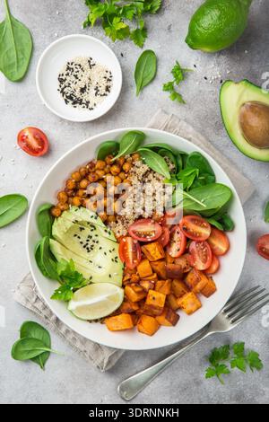 Gesunde vegane Mittagsschale. Avocado, Quinoa, Süßkartoffeln, Tomaten, Spinat und Kichererbsen Gemüsesalat Stockfoto