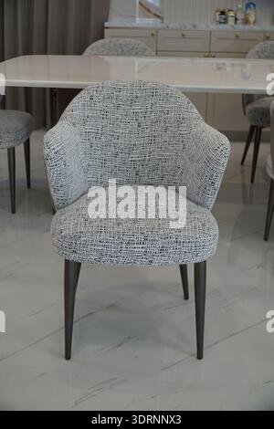 Stuhl mit weißem und schwarzem Muster steht vor einem Tisch. Der Stuhl ist aus Metall und hat ein modernes Design. Der Tisch ist auch aus Metall und Stockfoto