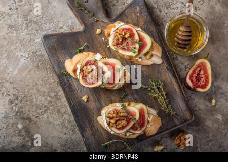 Bruschetta mit Ziegenkäse, Feigen, Nüssen und Honig auf Schneidebrett Stockfoto