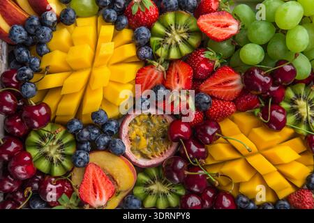 Köstliche Platte mit Früchten und Beeren. Mango, Kiwi, Erdbeere, Traube, Kirsche, Heidelbeere, Pfirsich und Passionsfrucht Stockfoto