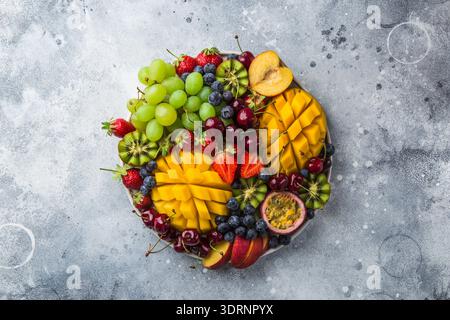 Köstliche Platte mit Früchten und Beeren. Mango, Kiwi, Erdbeere, Traube, Kirsche, Heidelbeere, Pfirsich und Passionsfrucht Stockfoto