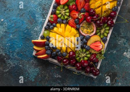 Köstliche Platte mit Früchten und Beeren. Mango, Kiwi, Erdbeere, Traube, Kirsche, Heidelbeere, Pfirsich und Passionsfrucht Stockfoto