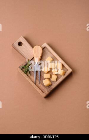 Gewürfelter Cheddar, Gouda oder Parmesankäse auf einem Schneidebrett. Gewürfelter Käse Stockfoto