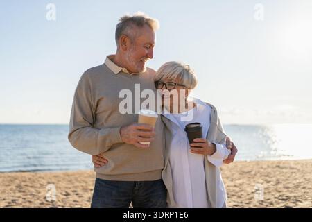 Guten Morgen. Älteres Ehepaar genießt es, mit Pappbecher Kaffee zu laufen. Die alte Ehefrau trinkt Kaffee, um nach draußen zu gehen. G Stockfoto
