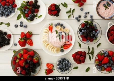 Farbenfrohe Frucht Collage mit verschiedenen Beeren und Joghurt auf weißem Holztisch Stockfoto