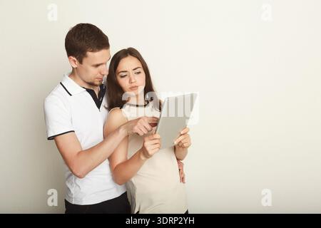 Ein Paar schaut sich das Tablet im Innenbereich während der Gelegenheitszeit zusammen an Stockfoto