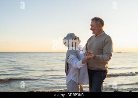 Bleiben Sie in Bewegung. Romantisches älteres Ehepaar, das gemeinsam am Strand im Freien tanzt. Glücklich lächelnde Familie pensionierte Mann Frau Stockfoto