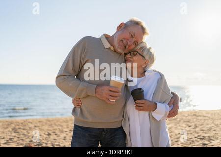 Guten Morgen. Älteres Ehepaar genießt es, mit Pappbecher Kaffee zu laufen. Die alte Ehefrau trinkt Kaffee, um nach draußen zu gehen. G Stockfoto