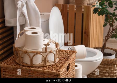 Tablett mit Toilettenpapierrollen auf Korb in der Toilette, Nahaufnahme Stockfoto