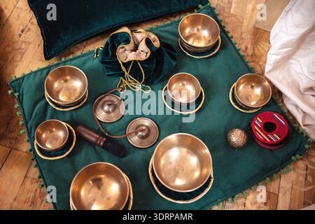 Sammlung von Messingschalen, die auf einer grünen Stoffmatte mit dekorativen Kanten angeordnet sind, mit einer kleinen Tasche und verschiedenen Gegenständen, cre Stockfoto