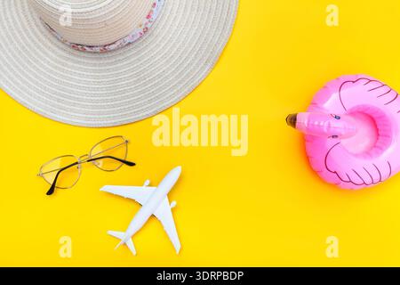 Sommerstrand. Minimaler einfacher flacher Lay mit flacher Sonnenbrille Hut und aufblasbarem Flamingo isoliert auf gelbem Hintergrund Stockfoto