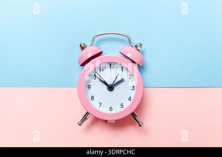 Vintage-Wecker isoliert auf blauem und rosa Pastellhintergrund Stockfoto