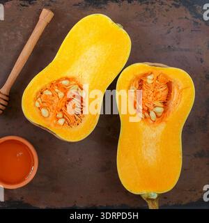 Hälften rohen Bio-Butternusskürbis auf Backform mit Honig Stockfoto