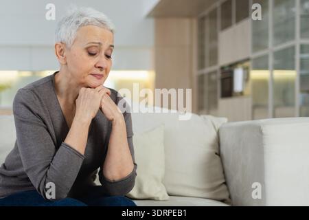 Traurig müde krank krank einsam enttäuschte ältere Frau, die allein zu Hause sitzt. Unglückliche reife Großmutter mit Trauer r Stockfoto