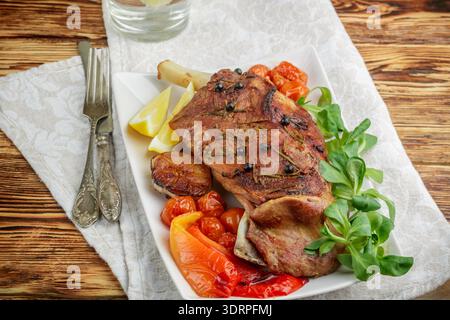 Im Ofen gebackenes Lamm mit Gewürzen - Rosmarin, Knoblauch und wacholder. Tomaten, Paprika und Kräuter. Das Gourmet-Abendessen. Selektiv f Stockfoto