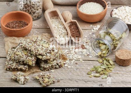 Gesunder Snack - knusprige Müsliekse auf altem Holztisch und Zutaten: haferflocken, Leinsamen, Kürbis, Sonnenblumen, Sesam. Di Stockfoto
