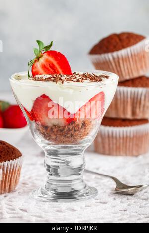 Mehrschichtiges Dessert aus Schokoladenschwammkuchen, Schlagsahne oder Ricotta und frischen Erdbeeren in einer Glasschale. Kleinigkeit. Köstliches Go Stockfoto