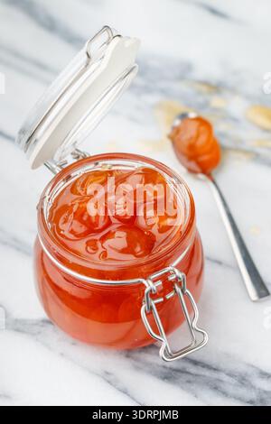 Hausgemachte köstliche süße Marmelade aus weißen Kirschen in einem Glas auf Marmorhintergrund. Ein Leckerbissen für Tee oder eine Füllung für Kuchen. Ch Stockfoto