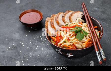 Udon-Nudeln mit Gemüse (Karotten, Paprika, Zucchini, Gurke, Zwiebeln, Koriander, Knoblauch), Ente und Sesamsamen. Das Rührwerk fr Stockfoto