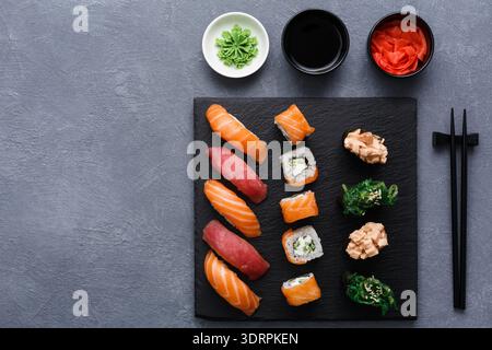 Frisches Sushi serviert auf einem schwarzen Teller mit Wasabi, Sojasauce und eingelegtem Ingwer Stockfoto