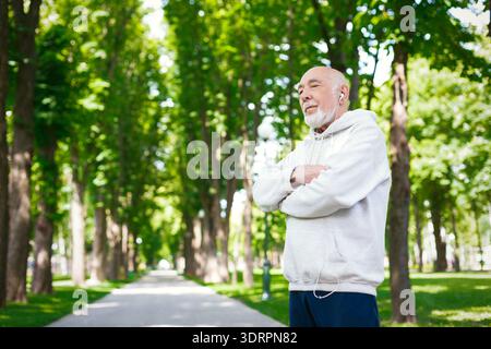 Senior man genießt Musik während er in einem Green Park während der Tageslichtstunden steht Stockfoto