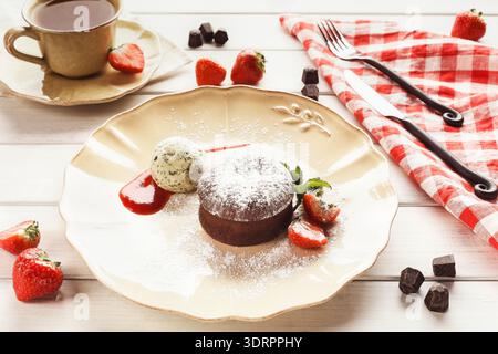 Schokoladendessert serviert mit Erdbeeren und Eis mit Kaffee auf dem Tisch Stockfoto