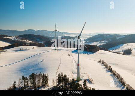 Windturbinen stehen im Winter auf einem schneebedeckten Feld und betonen so robuste Energiesysteme, die in kalten Klimazonen betrieben werden können. Stockfoto