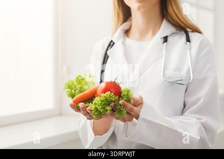 Ein Mediziner hält frisches Gemüse, darunter Tomaten, Karotten und Blattgemüse Stockfoto