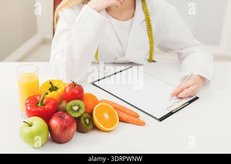 Ernährungswissenschaftler erstellt einen Plan mit Obst und Gemüse auf dem Tisch in einer Küche Stockfoto