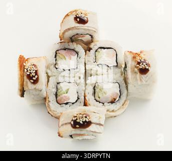 Sammlung von Sushi-Rollen, die in einem Kreismuster auf einer weißen Oberfläche angeordnet sind Stockfoto