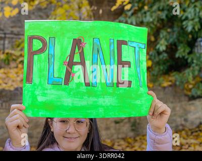 Piacenza, Italien - 3. Februar 2022 Mädchen mit einem handgefertigten grünen Schild, auf dem DER PLANET steht, das Maßnahmen gegen den Klimawandel und die Umweltverschmutzung fordert Stockfoto