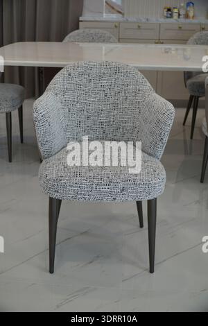 Stuhl mit weißem und schwarzem Muster steht vor einem Tisch. Der Stuhl ist aus Metall und hat ein modernes Design. Der Tisch ist auch aus Metall und Stockfoto