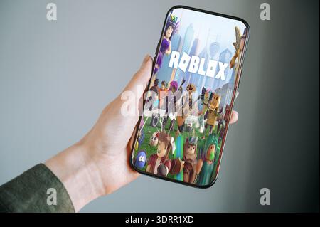 Riga, Lettland - 2. Februar 2026: Nahaufnahme einer Hand, die ein modernes Smartphone hält und die Roblox App-Oberfläche anzeigt. Konzeptbild mobiler Spiele, d Stockfoto
