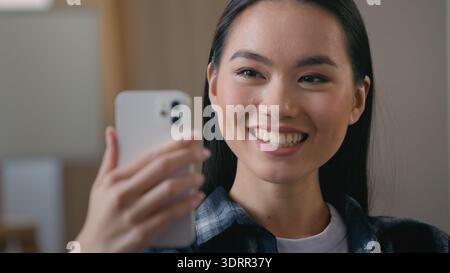 Glückliches asiatisches koreanisches Mädchen Frau lächelnd winkende Hand sprechendes Handy Videoanruf zu Hause Chinesische japanische Frau sprechende Webcam virtueller Chat online Stockfoto