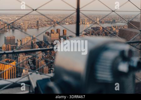 Besucher beobachten die Skyline von New York City bei Sonnenuntergang durch ein Teleskop Stockfoto