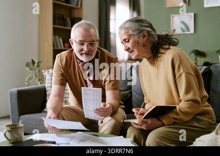 Senior-kaukasischer Mann und Senior-kaukasische Frau überprüfen gemeinsam Finanzdokumente Stockfoto