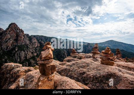 Ausgewogene steinhügel auf felsigem Berggelände mit bewaldeten Hügeln und dramatischem bewölktem Himmel im Hintergrund, geeignet für Reisen, Natur, Wandern, und Stockfoto