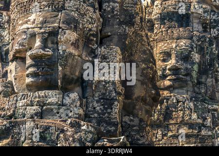 Nahaufnahme von drei riesigen Steinwänden am Bayon-Tempel, seitlicher und frontaler Blick in Angkor, Siem Reap, Kambodscha Stockfoto