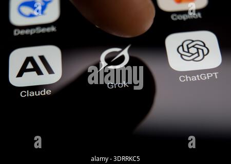 Auf einem Smartphone-Bildschirm werden die Anwendungssymbole DeepSeek, Grok, Claude und ChatGPT angezeigt, die einen Finger zeigen, der dabei ist, einen KI-Chatbot aus einer Div auszuwählen Stockfoto