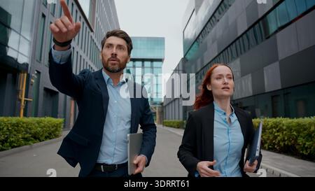 Kaukasische Geschäftskollegen gehen in die Stadt Check-Zeit späte Besprechung eilige Geschäftsleute Kollegen Partner Manager Geschäftsfrau Geschäftsmann Stockfoto