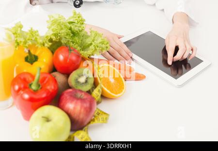 Sammlung gesunder Lebensmittel und Technologie bei einer Diätberatungssitzung Stockfoto