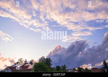 Sanfte rosa und goldene Wolken über den Dächern der kleinen Stadt bei Sonnenuntergang. Stimmungsvoller Abendhimmel mit Kopierraum. Bayern Stockfoto