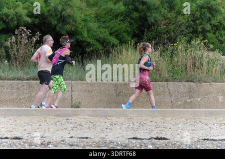 Freunde joggen an einem Sommertag in großbritannien entlang der Küste Stockfoto