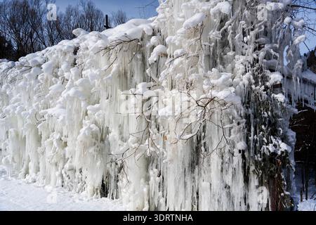 Eine dramatische gefrorene Landschaft mit einer dicken Wand aus langen Eiszapfen und starkem Schnee, der sich an Ästen festhält. Stockfoto