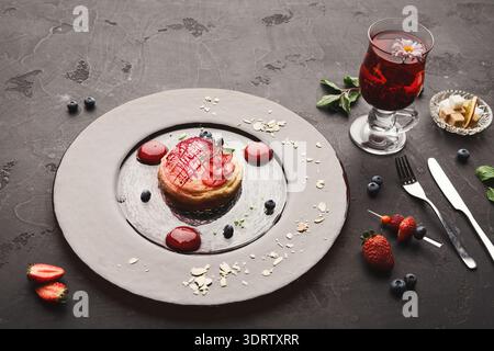 Köstliches Dessert und Getränk serviert auf einem Teller mit Obst und Dekorationen in einem Speisesaal Stockfoto
