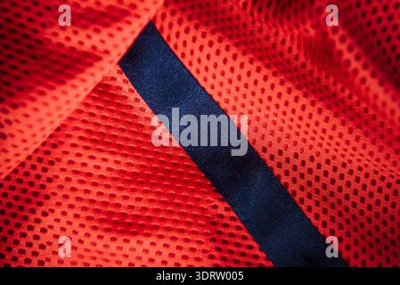 Rotes technisches Sport-Mesh-Material mit diagonalem marineblauen Streifen-Makrohintergrund für die Herstellung von Sportbekleidung und atmungsaktives Textildesign Stockfoto