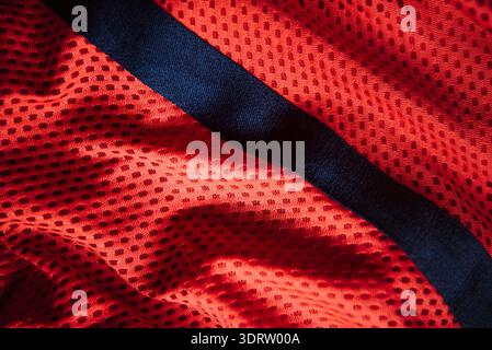 Rotes technisches Sport-Mesh-Material mit diagonalem marineblauen Streifen-Makrohintergrund für die Herstellung von Sportbekleidung und atmungsaktives Textildesign Stockfoto